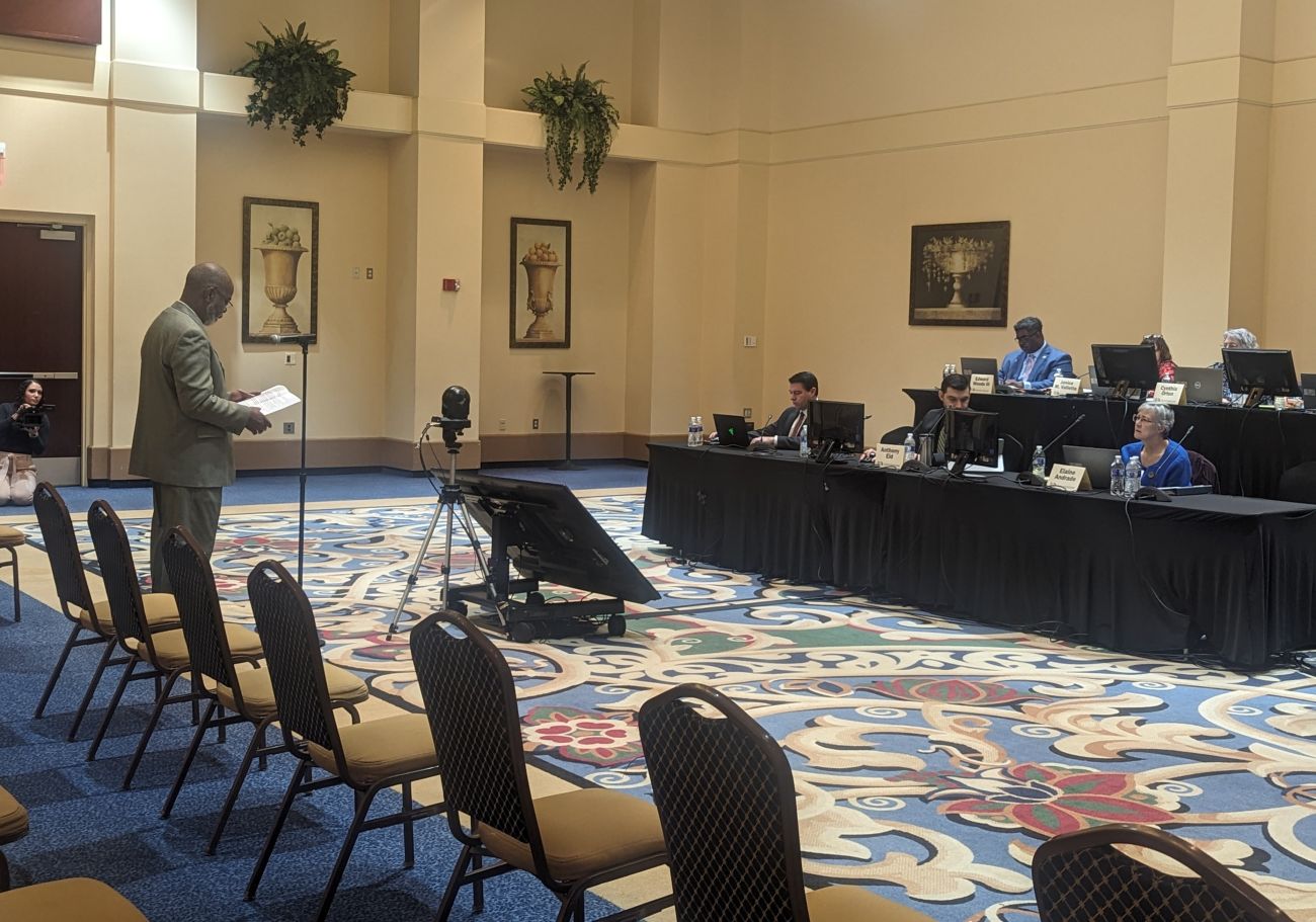 attendee speaks to people sitting at a table