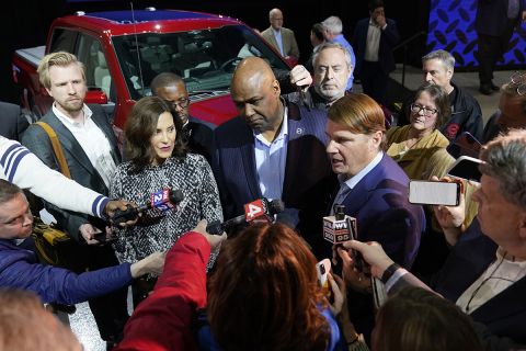 Michigan Gov. Gretchen Whitmer at a press conference. Reporters surround her and others. 