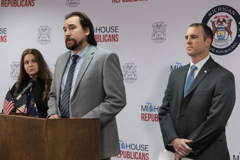 Michigan Rep. Brad Paquette is at a podium. Sen. Thomas Albert stands behind him.