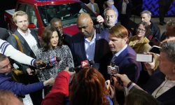 Michigan Gov. Gretchen Whitmer at a press conference. Reporters surround her and others. 